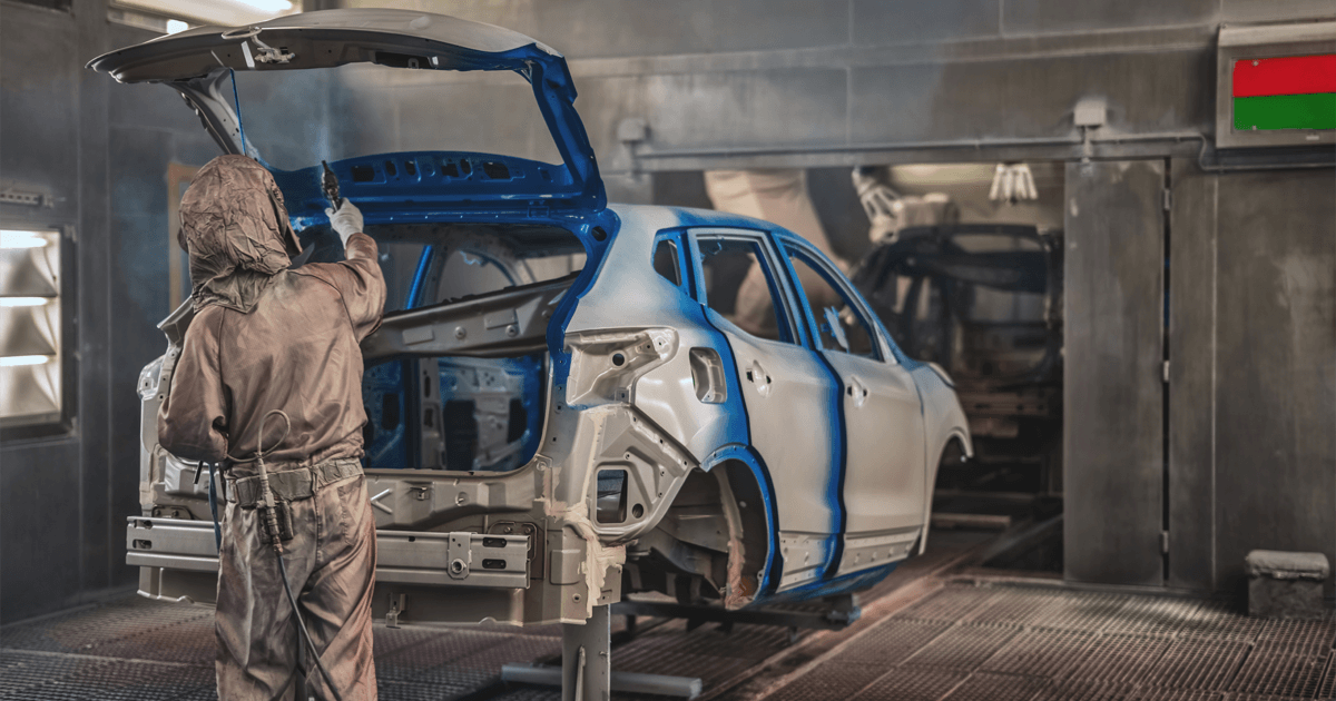 Car body shop - mechanic with protective clothes painting a car