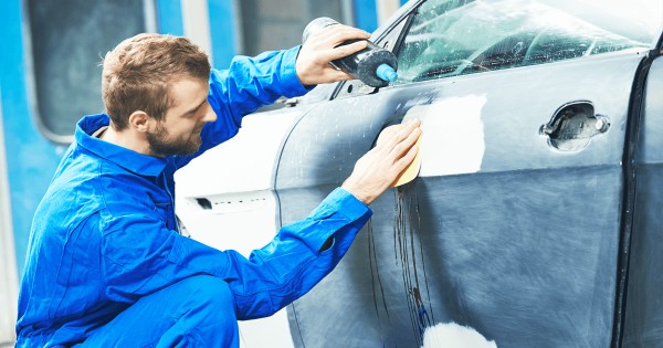 Car body shop - mechanic preparing a blue car for painting